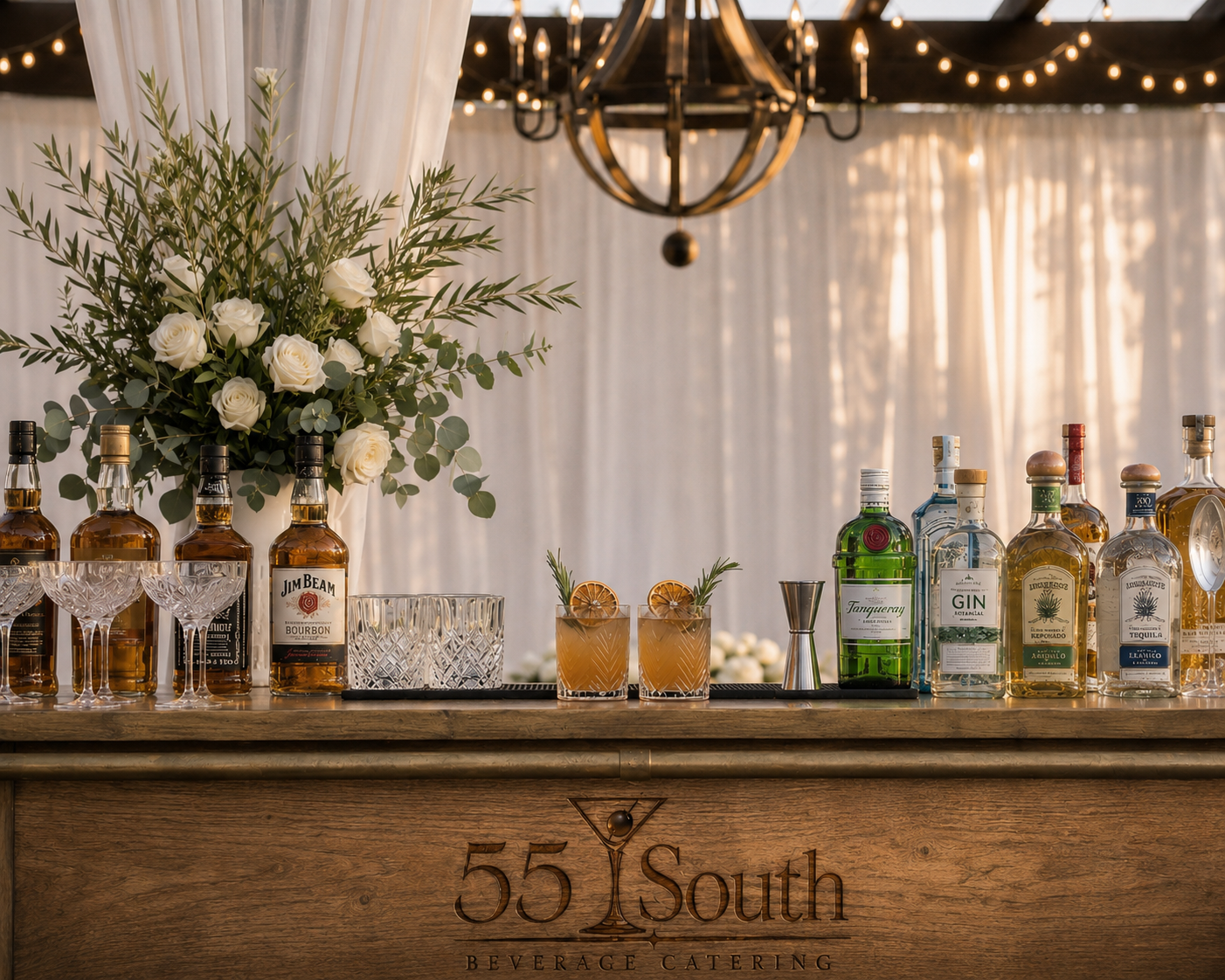 55 South bar at a wedding, engraved logo on the wood front with cocktails and florals on top
